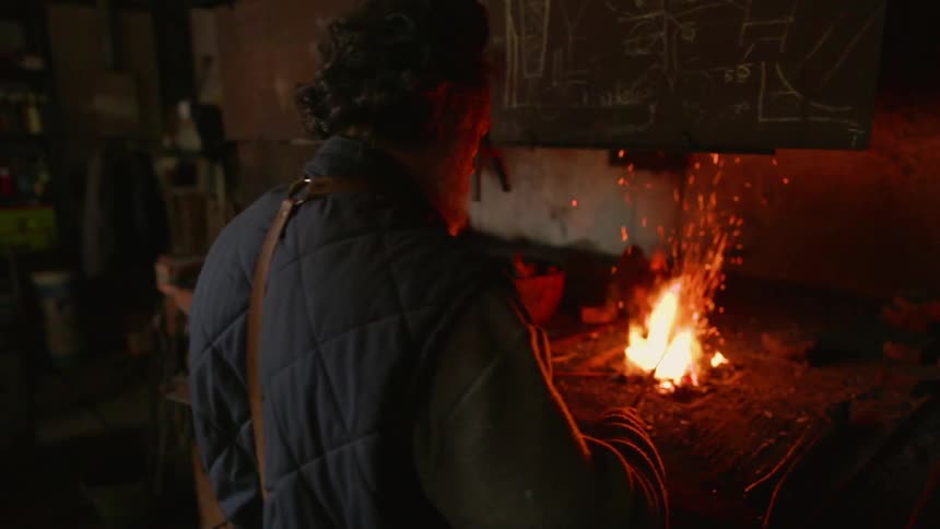 A man is stoking a fire inside a forge