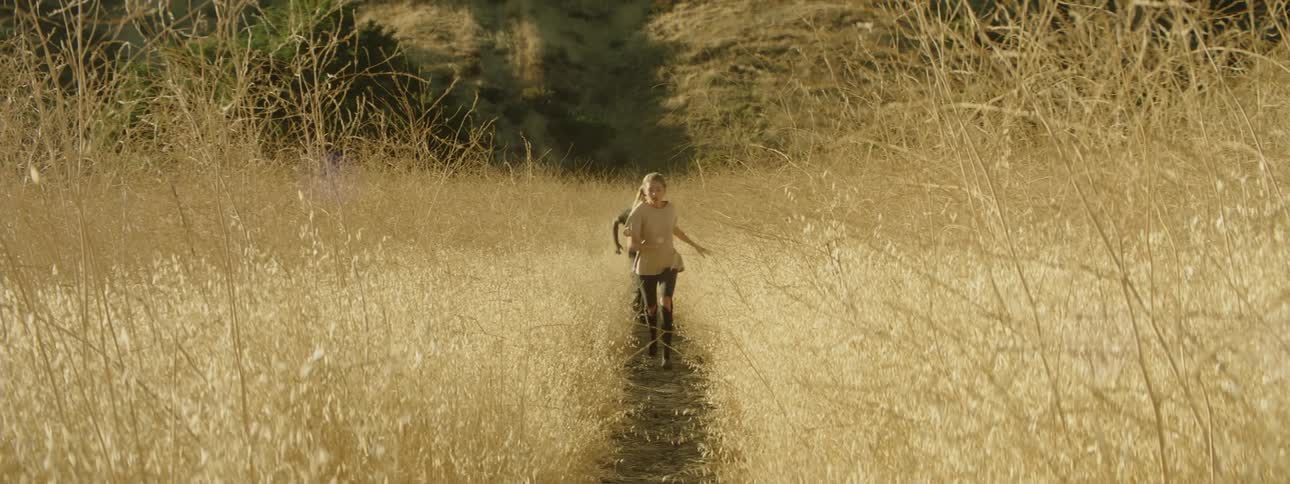 A woman and man run through a rural field