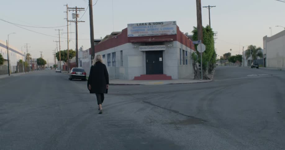 A woman is walking across a street in a city near dusk
