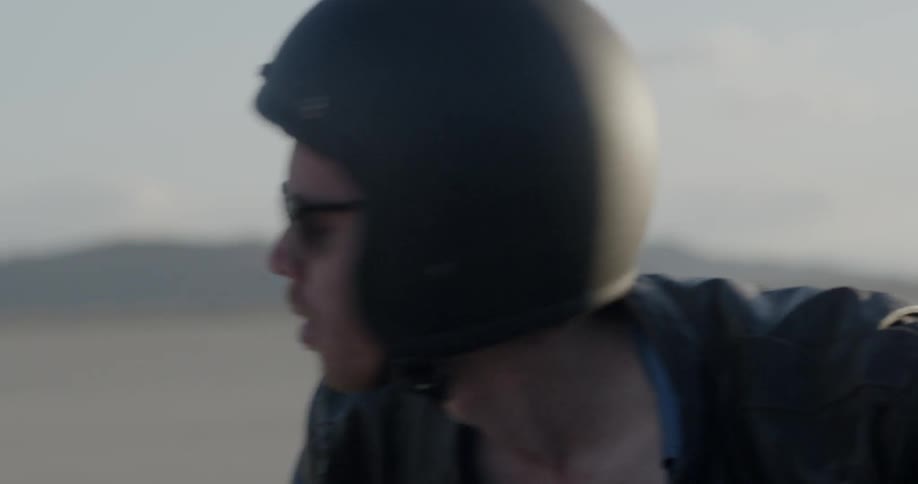 Man rides motorcycle through flat desert