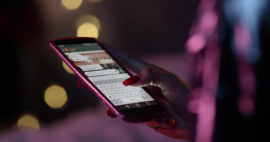 A woman is texting on her mobile phone outside at night