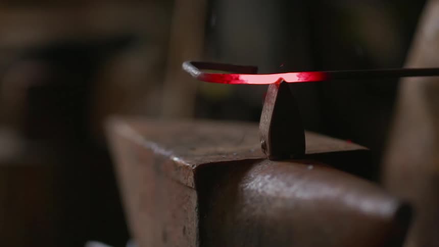 A blacksmith is hammering metal on an anvil