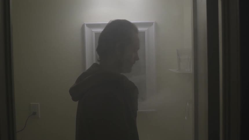 Man standing near a mirror with smoke all around him