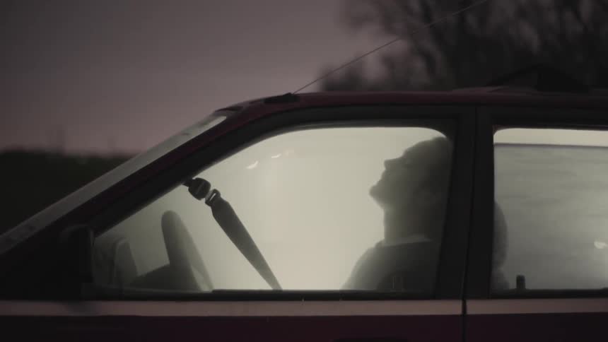 A man sits in a car that is filled with smoke