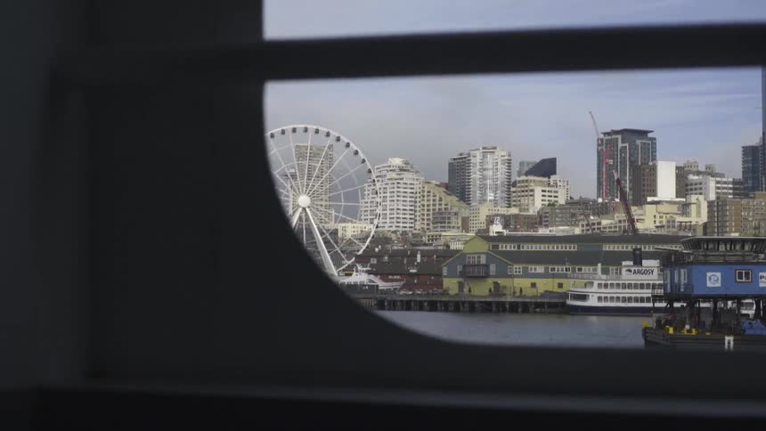 A citys waterfront is viewed from aboard a vehicle crossing a bridge with storm clouds approaching
