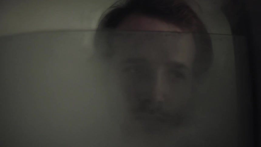 Man stands behind glass with smoke all around him