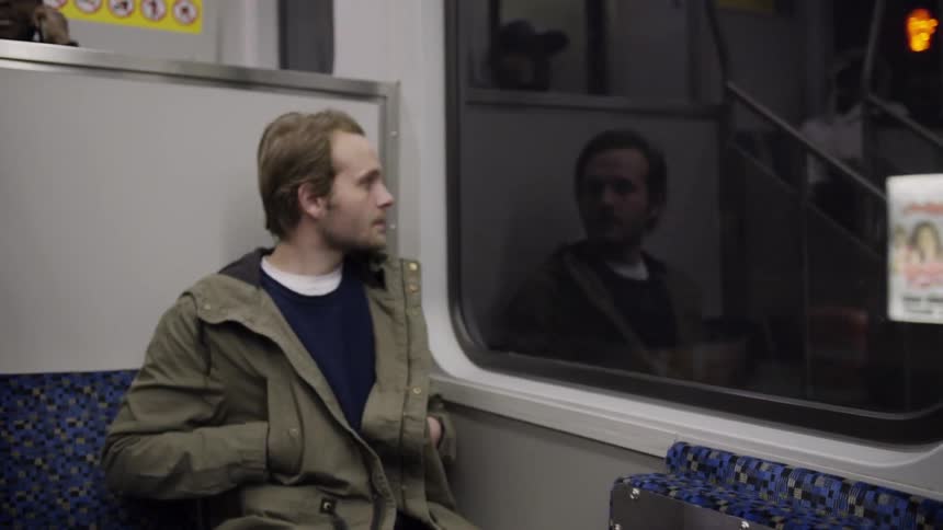 A man takes a seat on a city bus and looks through the window