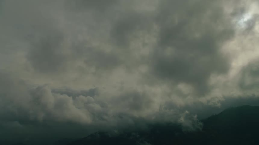 Clouds are drifting over a mountain range in daylight