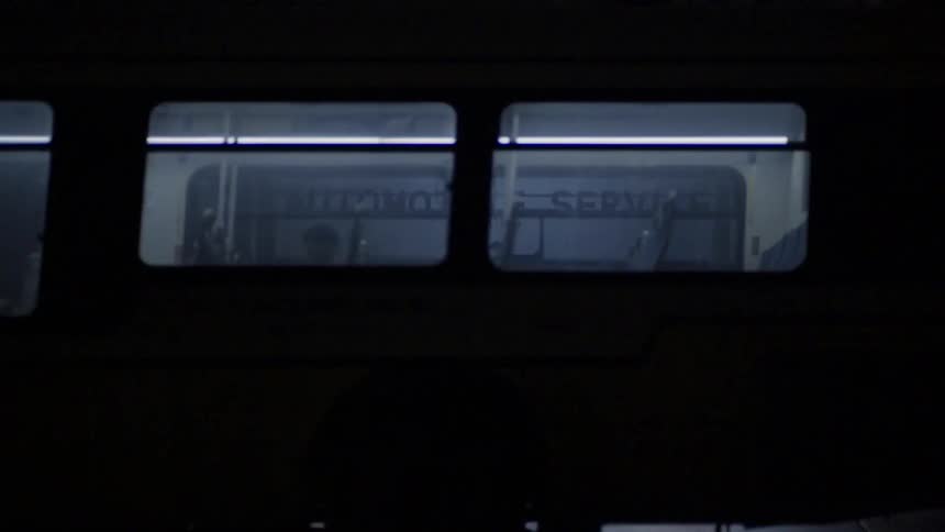 A white male stands in front of a business as a bus drives past