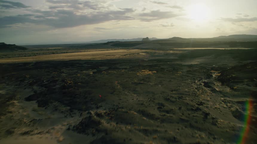 Sun shines over flat grassy and muddy land