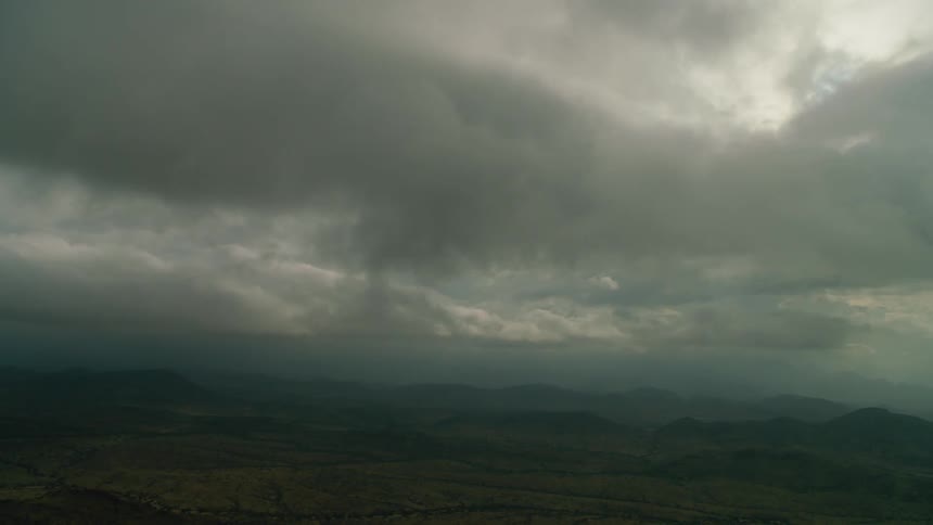 Sun shines behind clouds over hilly and flat land