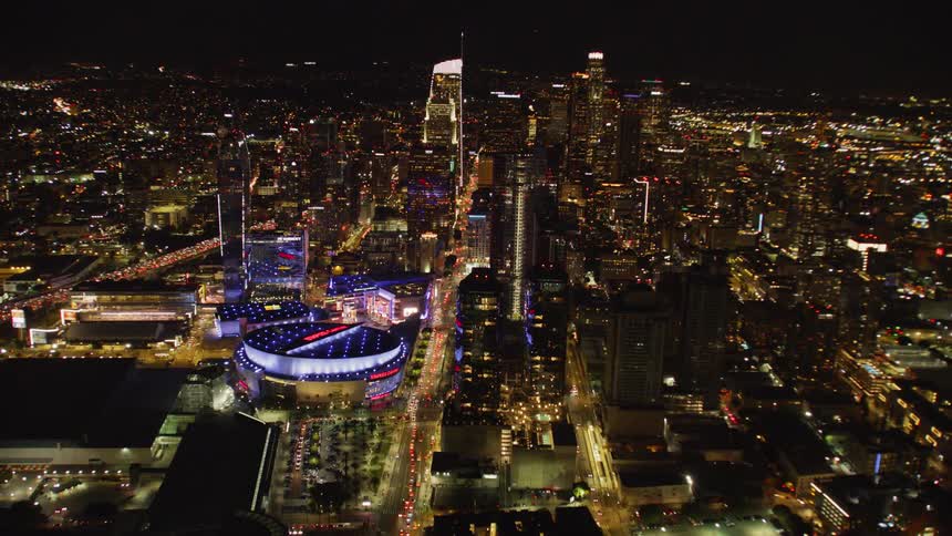 The stadium is brightly lit in blue and red at night; Los Angeles