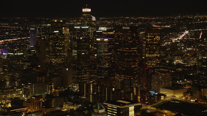 The row of tall buildings are all brightly lit at night