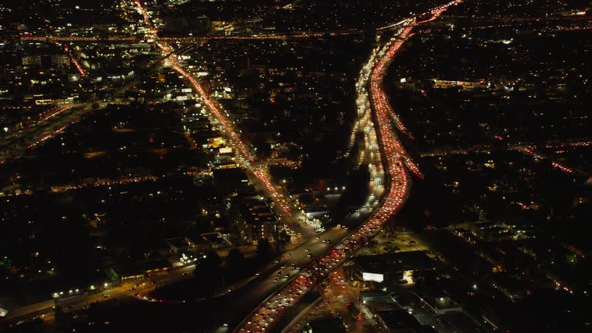 Traffic is flowing on a freeway system in an urban area at night