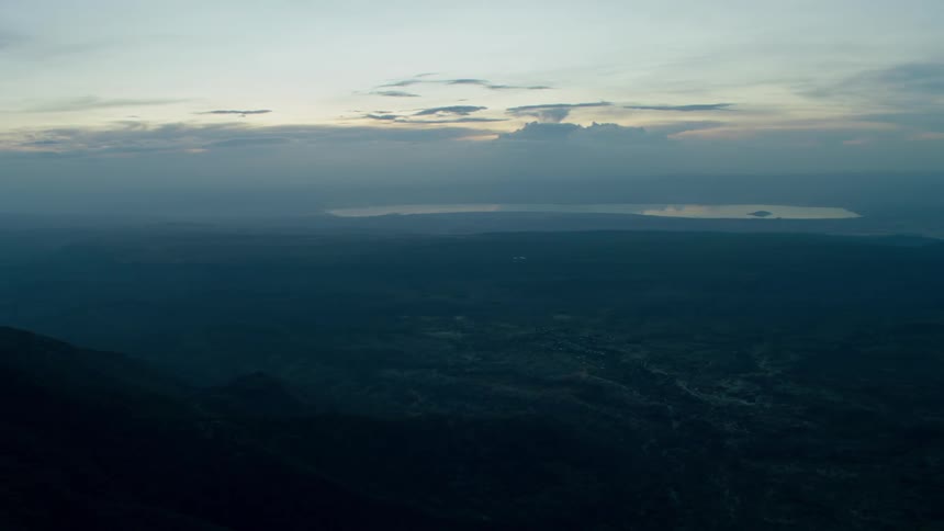 Clouds float above a mountain landscape at sunset