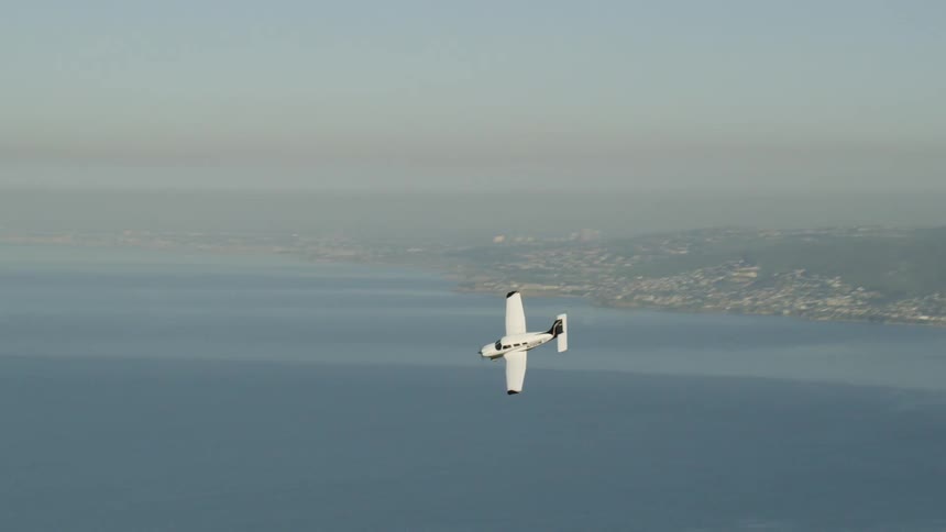A small plan flies over the water