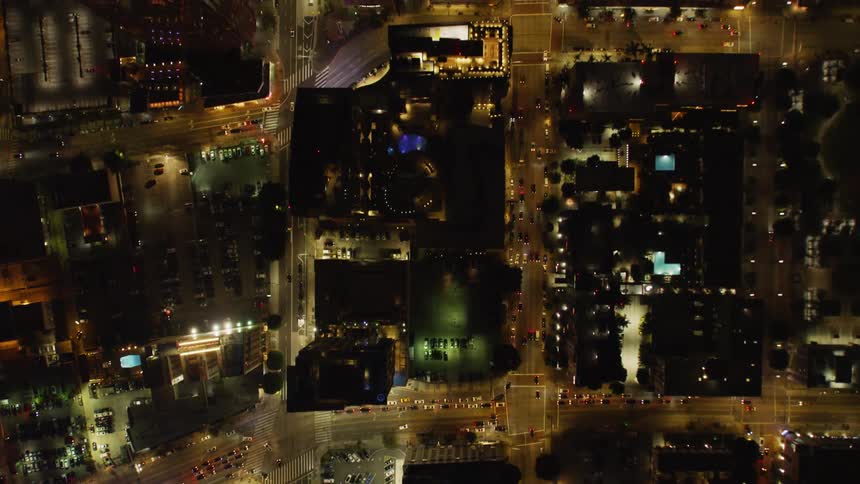 Cars drive on city streets at night