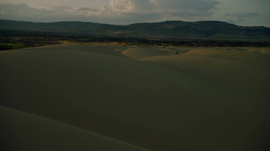 Sun sets over sandy hilly land