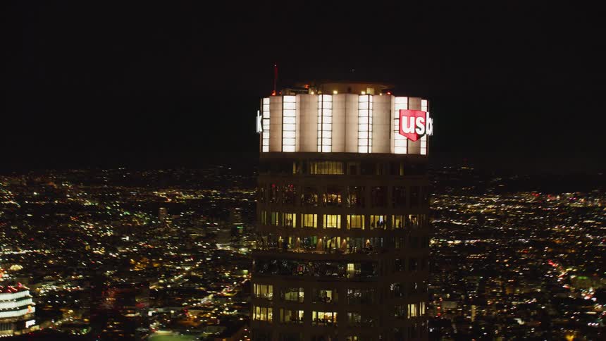 A skyscraper sign is lit up in a city at night