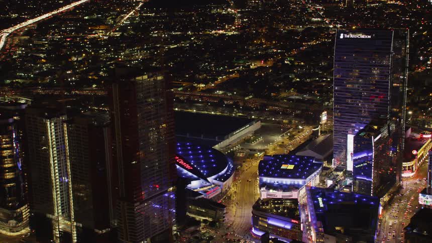 The stadium is surrounded by buildings at night