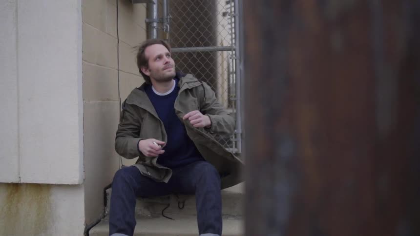 Man sits down on stone steps then looks up