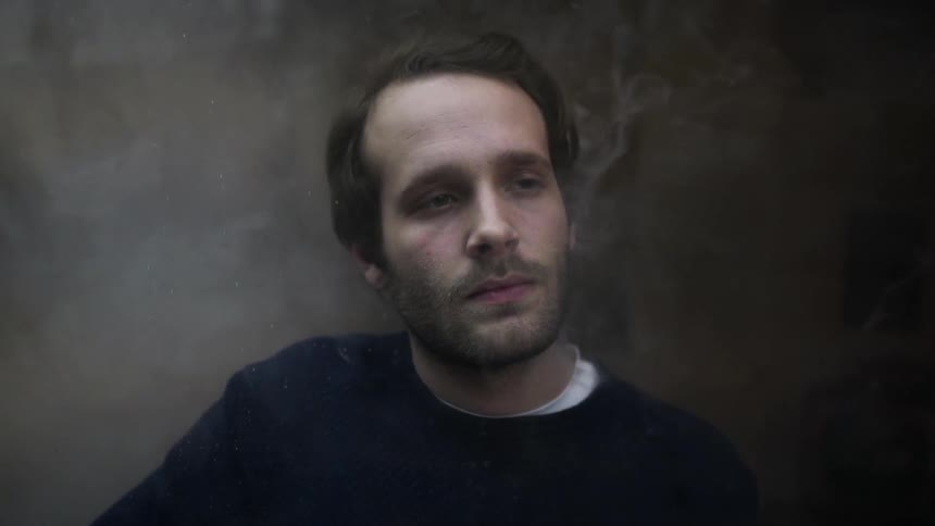 A man sits in a smoky environment