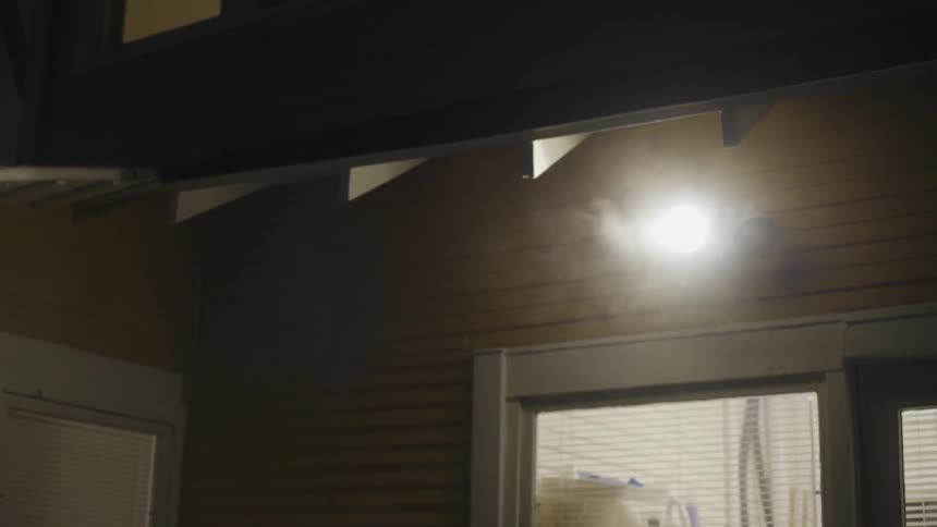 Smoke comes out of the edge of the roof of a house at night
