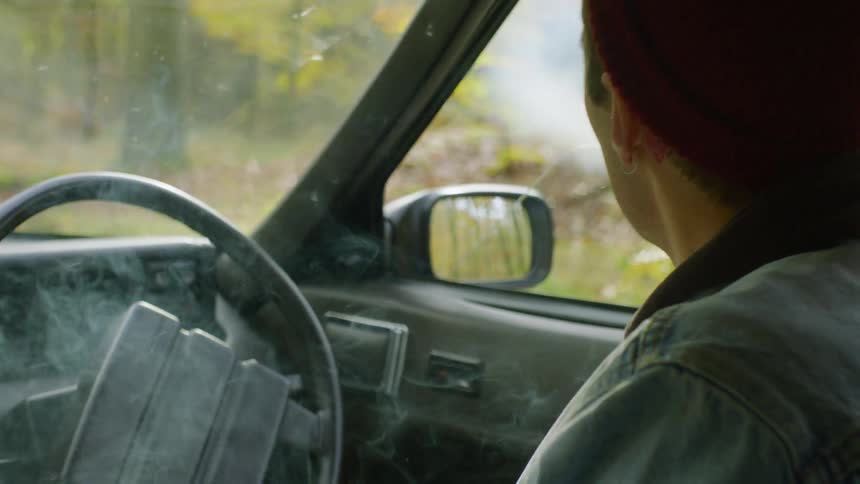 A man smokes a cigarette in a car