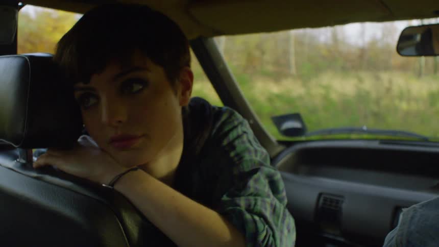 The girl leans back looking into the backseat of the moving car