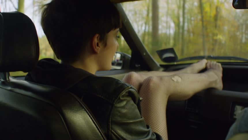 A woman puts her feet up on the dash of the car