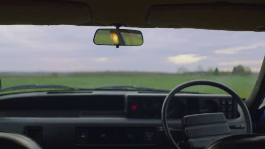 A man and woman park in a rural field