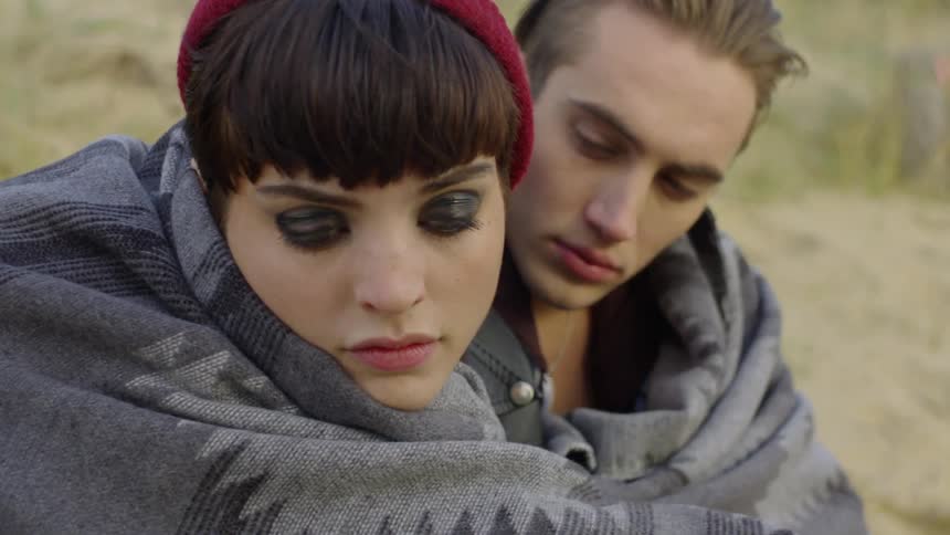 Man and woman cuddle in a blanket
