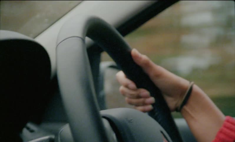 Person's hand grips a steering wheel while driving
