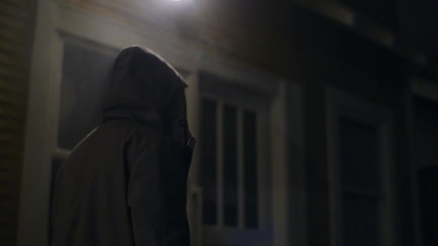 A man is walking down the street at night