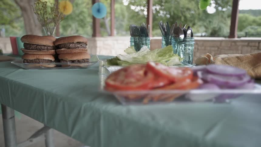 Burgers and condiments are served at a cookout