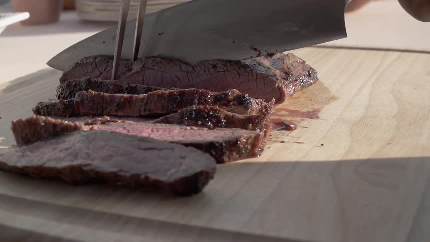 Person slicing cooked meat on a cutting board