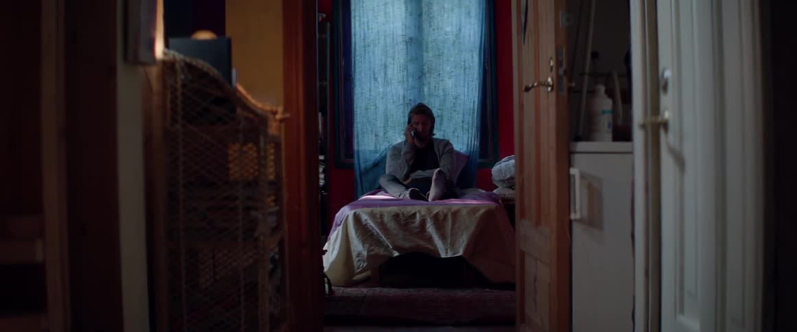 Wide shot of a male character using his mobile phone inside bedroom.