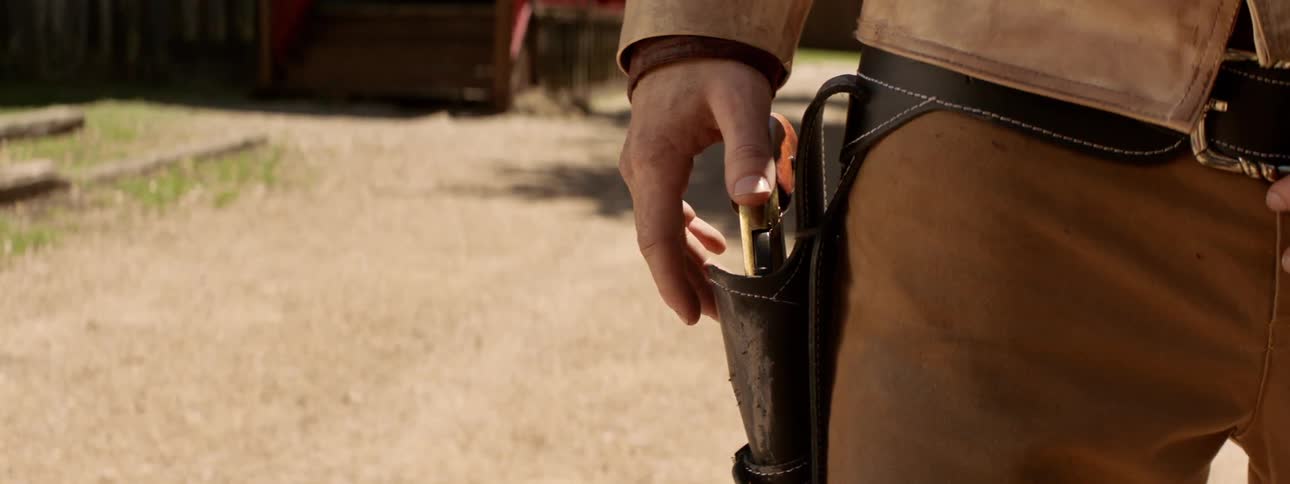 A man rests his hand on a holstered gun ready to draw