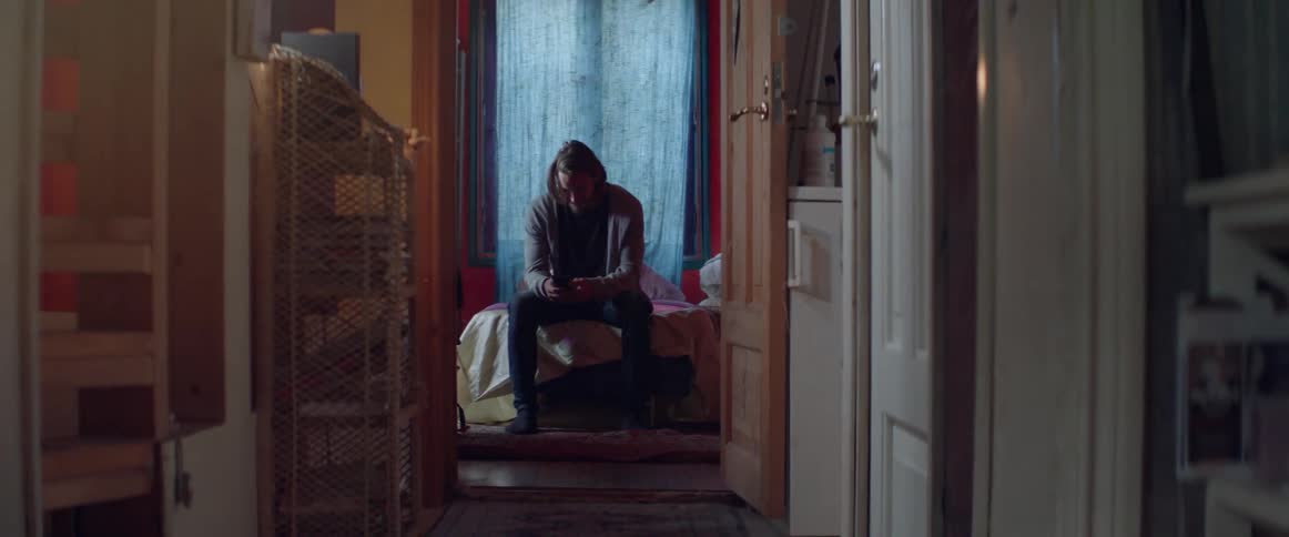Distant shot captures a lonely male character checking notifications on his cell phone.