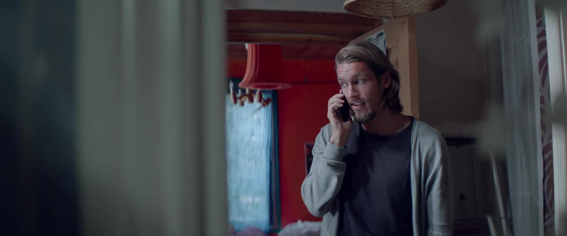 A handsome male character smiles warmly while speaking on a cell phone tonight.