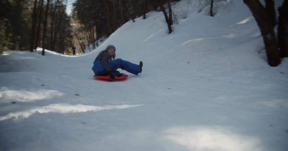 Woman slides down a snowy path on a red saucer