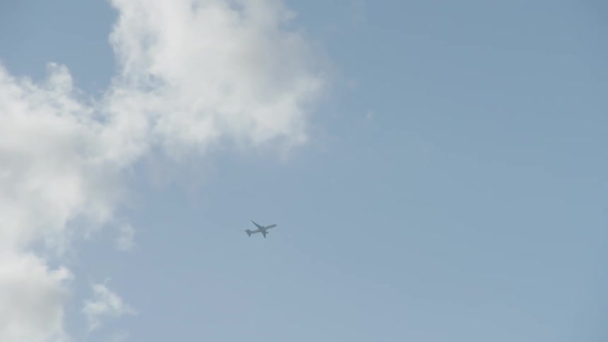 Large jet flying out of some clouds and into a clear sky