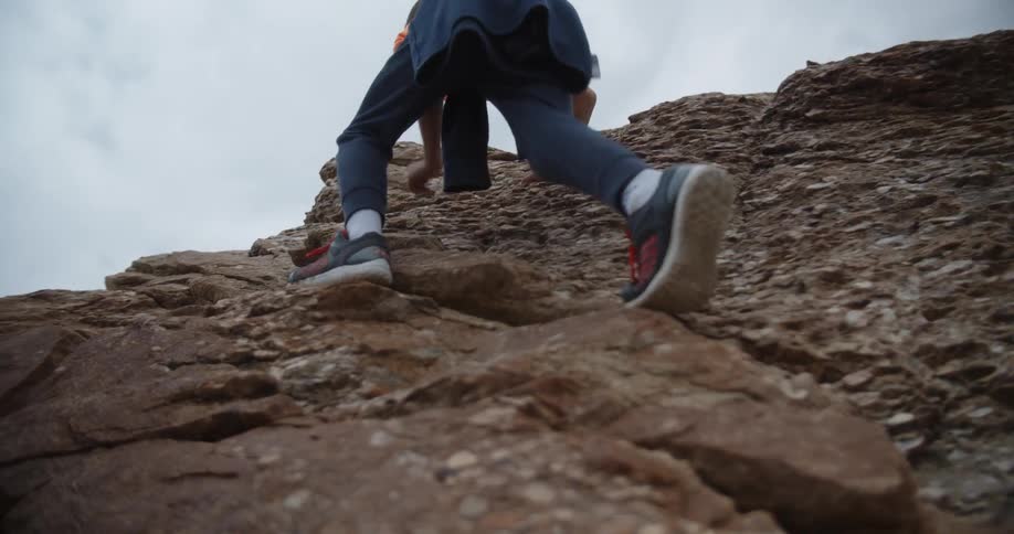 Two children climb up the steep rocks