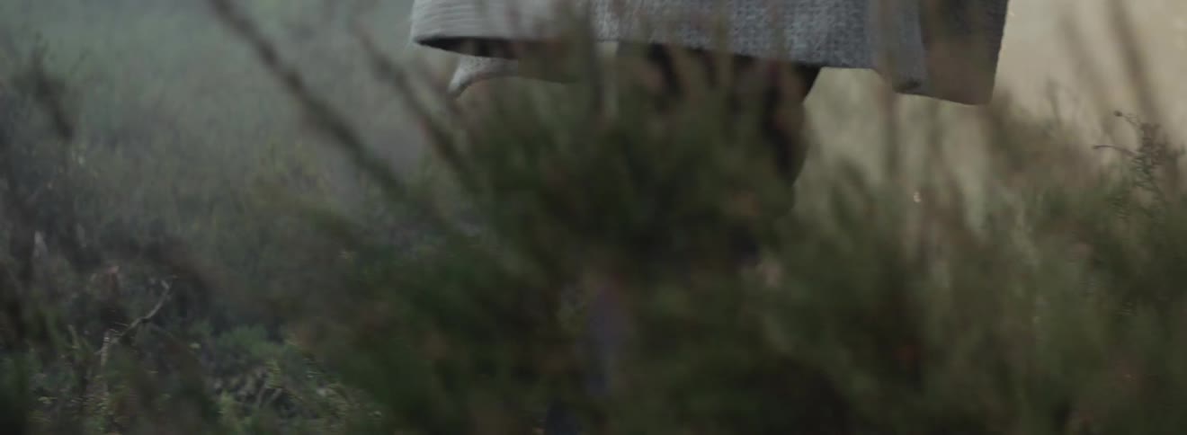 A person steps over plants in a rural field