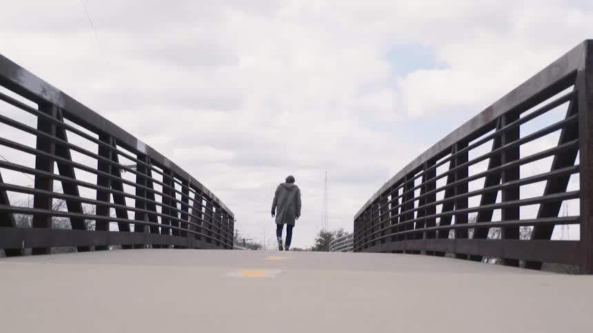 Person walking across a small bridge on a cloudy day