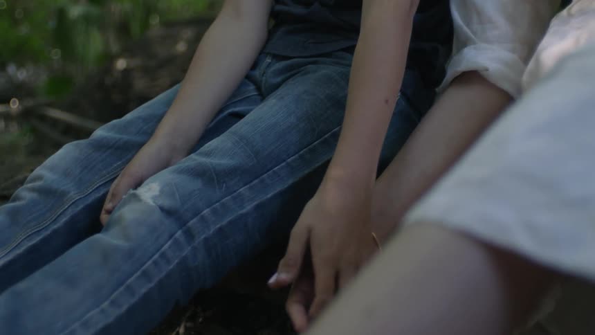 Two people sit and hold hands