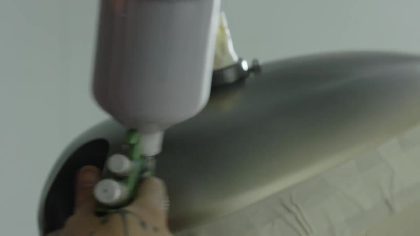 A person is spray painting a piece of metal