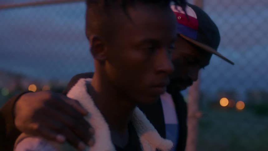 A man consoles a younger man while walking