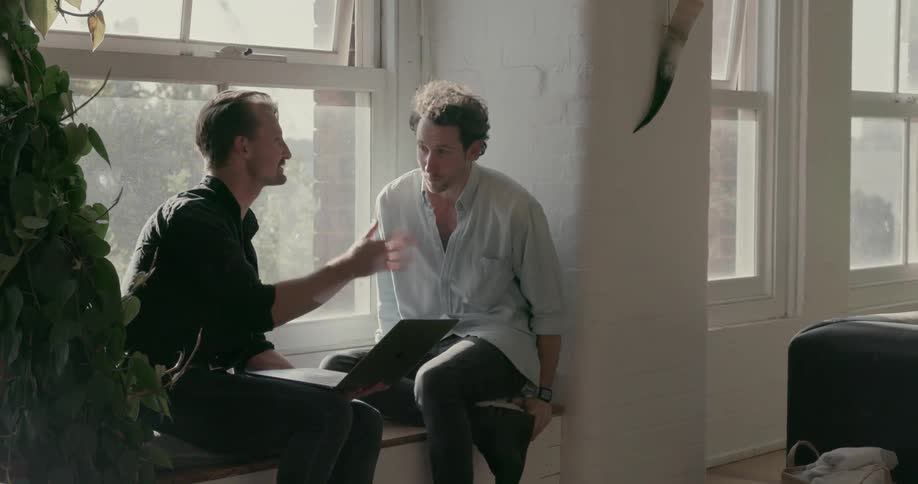 Two men talk on a window seat
