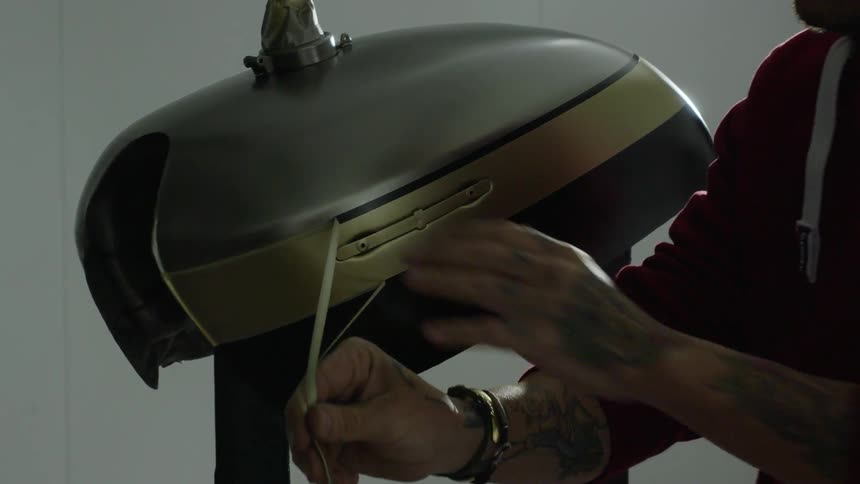 A man peels the tape off freshly painted metal